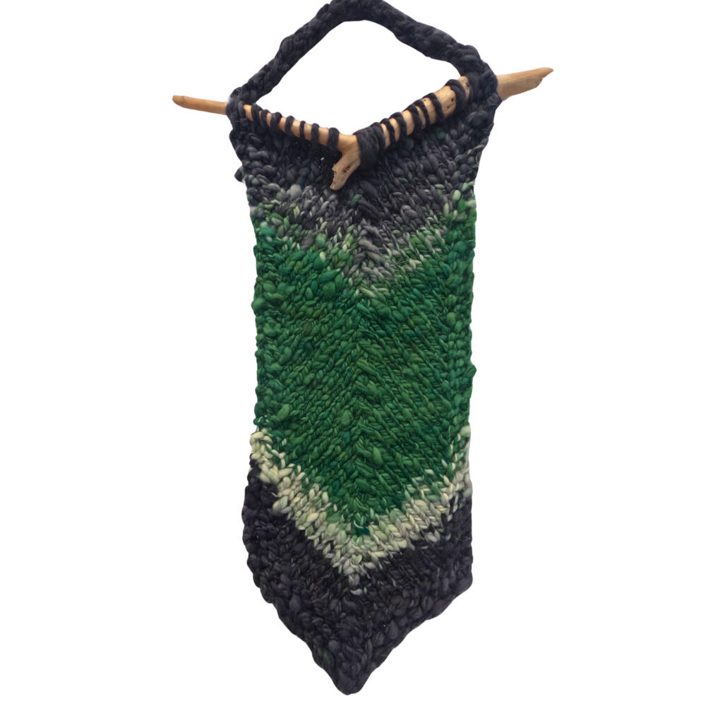hanspun variagated wool in green, black and white knit into a chevron hung on V-shaped stick